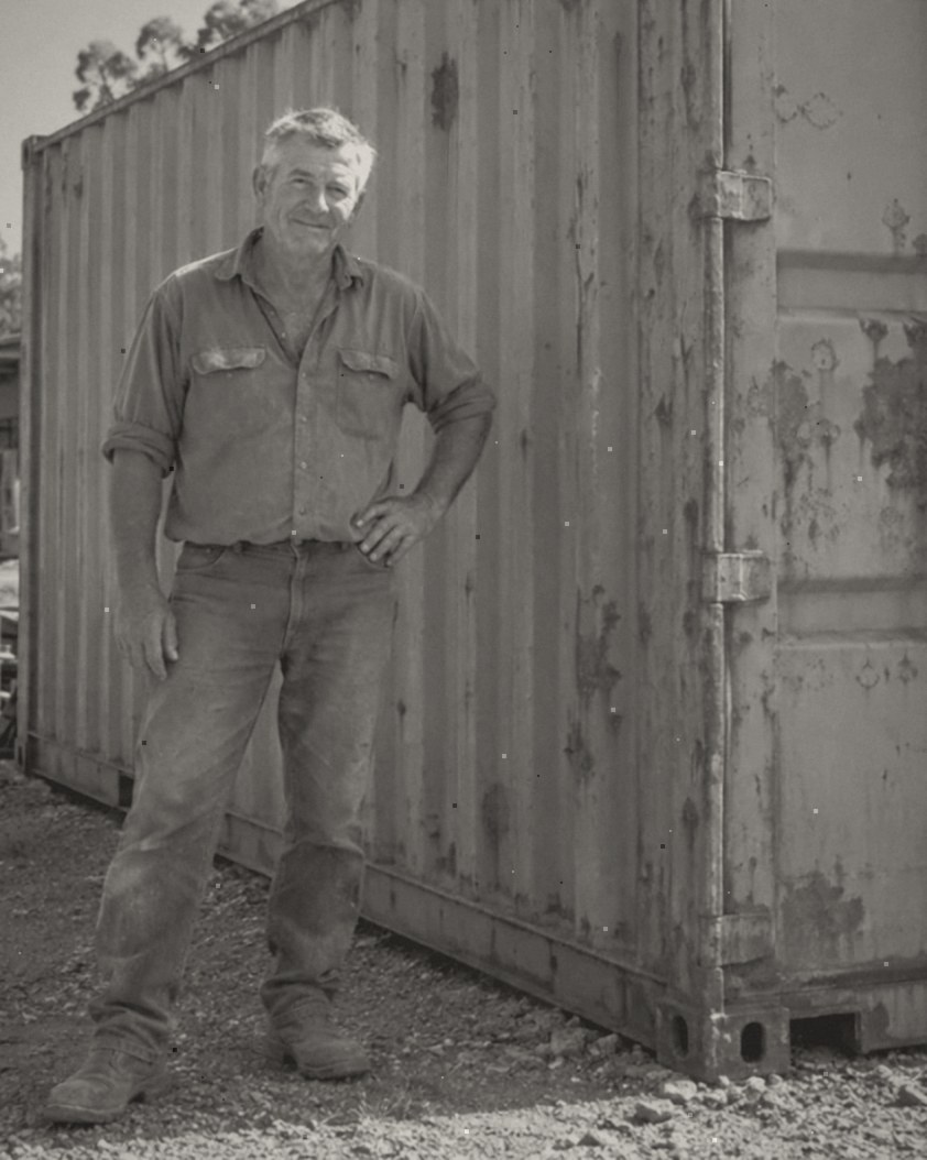 Black and white photo of the D & B Solutions owner standing beside a shipping container in the yard