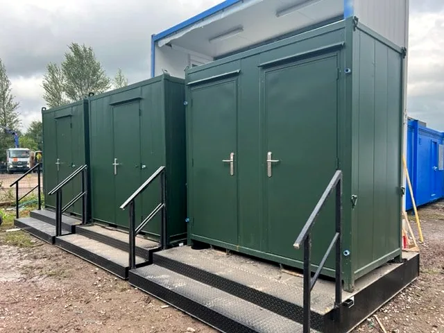 Three green steel units on raised platforms with steps and handrails.