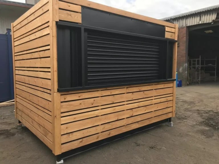 Compact timber-clad container kiosk with roller shutter