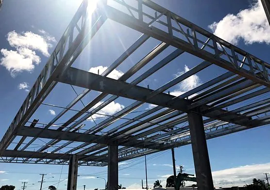 Steel canopy framework viewed from below against a blue sky.