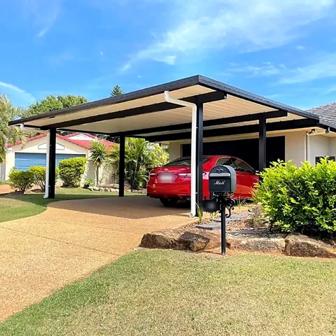 Flat-roof carport over a house driveway with a red car underneath.