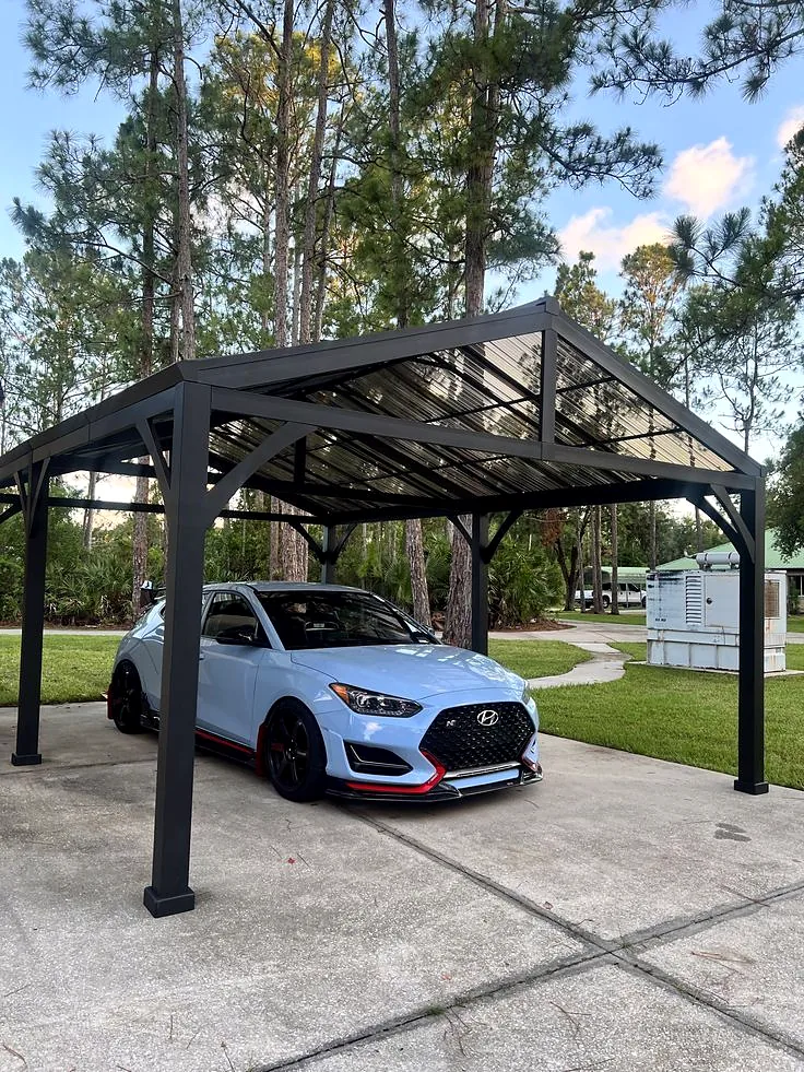 Charcoal steel gable-roof carport over a concrete pad with a car parked under it.