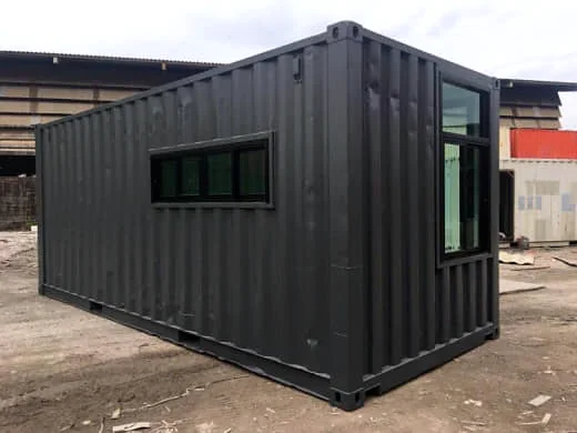Black shipping container with a long horizontal window on the side and a tall window on the end.