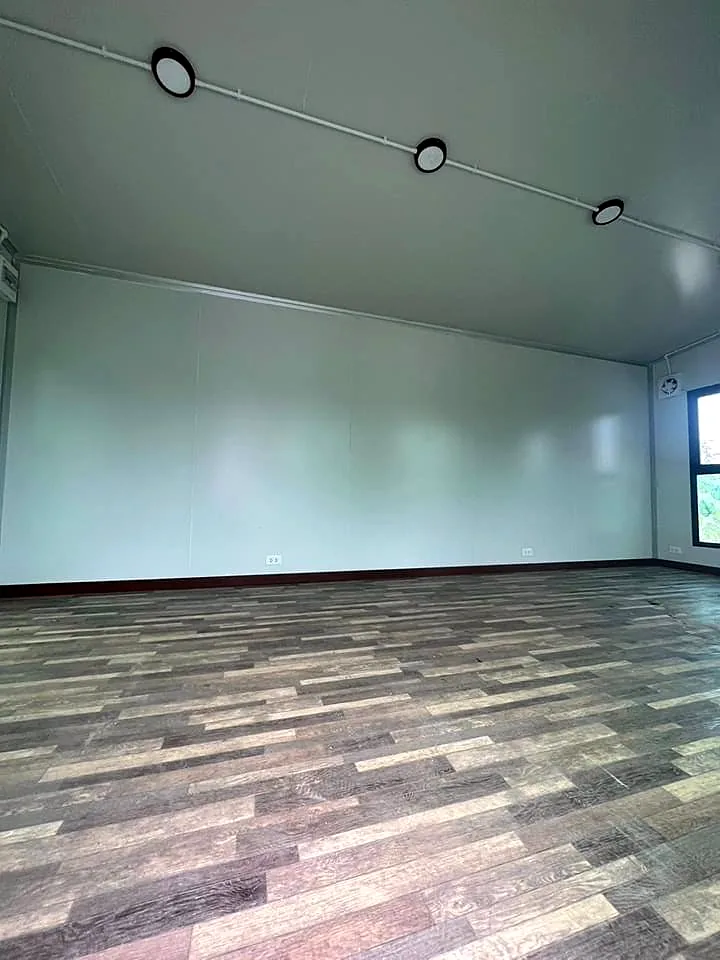 Empty interior wall with ceiling lights and multi-tone plank floor.