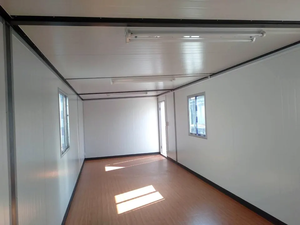 Empty modular interior with fluorescent ceiling lights, white walls and timber-look floor.