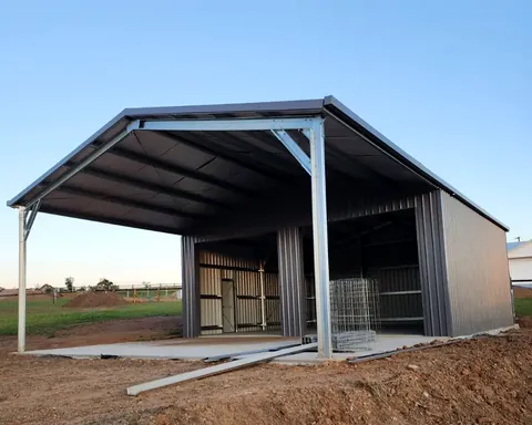 Grey steel shed with a large open bay and skillion roof on a new concrete slab.
