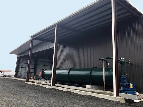 Open-sided steel shed covering green industrial machinery.
