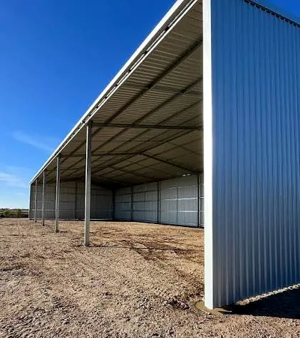 Large steel shed with an open front and long roof, under a blue sky.